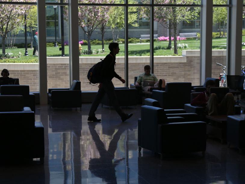 A student wearing a backpack walks across the first floor of Smith Hall.
