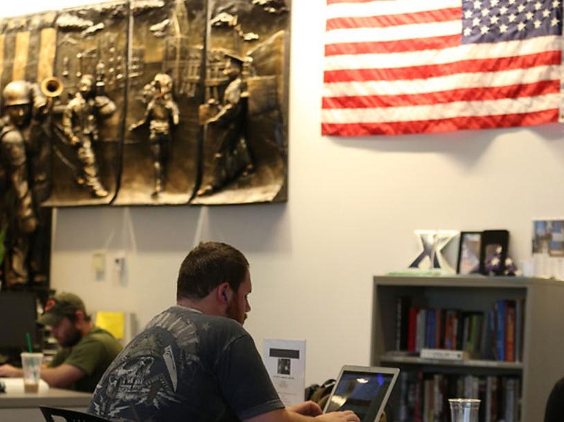 A student studying in the Veteran and Military Family Center. There is an American Flag in the background.