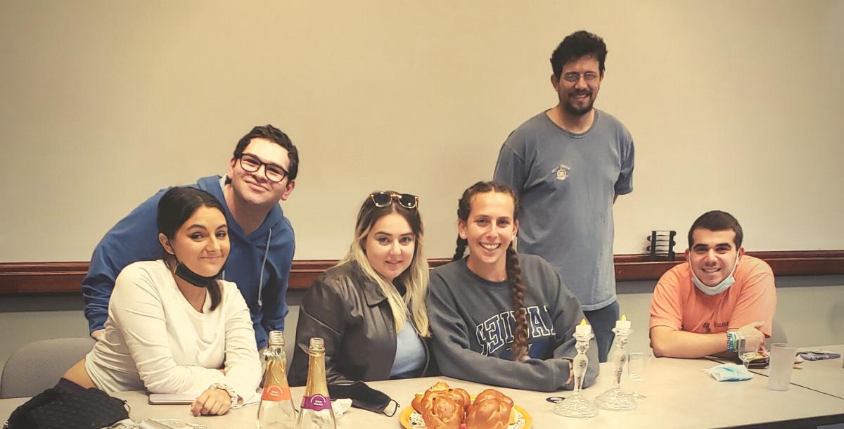 Six students gathered with challah and candles for Shabbat in Gallagher