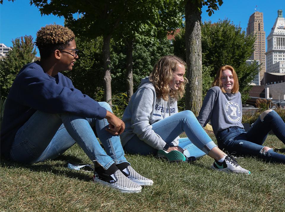 Three Xavier students sitting outside together at a park in downtown, Cincinnati