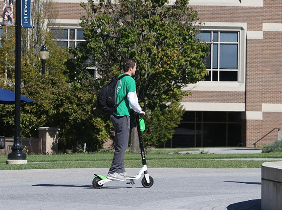 Xavier student on a scooter on campus