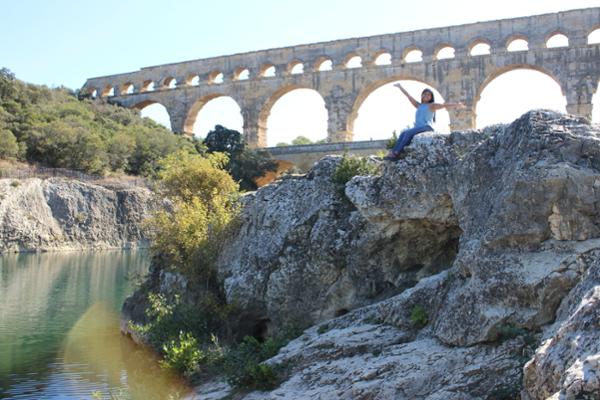 Photo of Student sitting on a small cliff in front of an Ancient Roman aqueduct