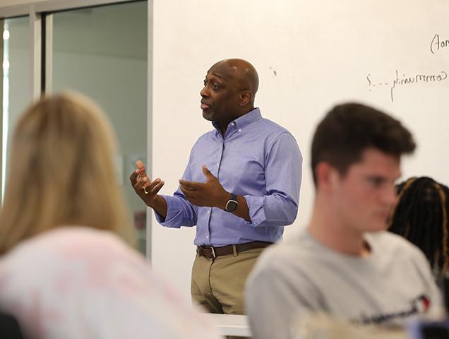 Professor leading a class in front of a chalkboard