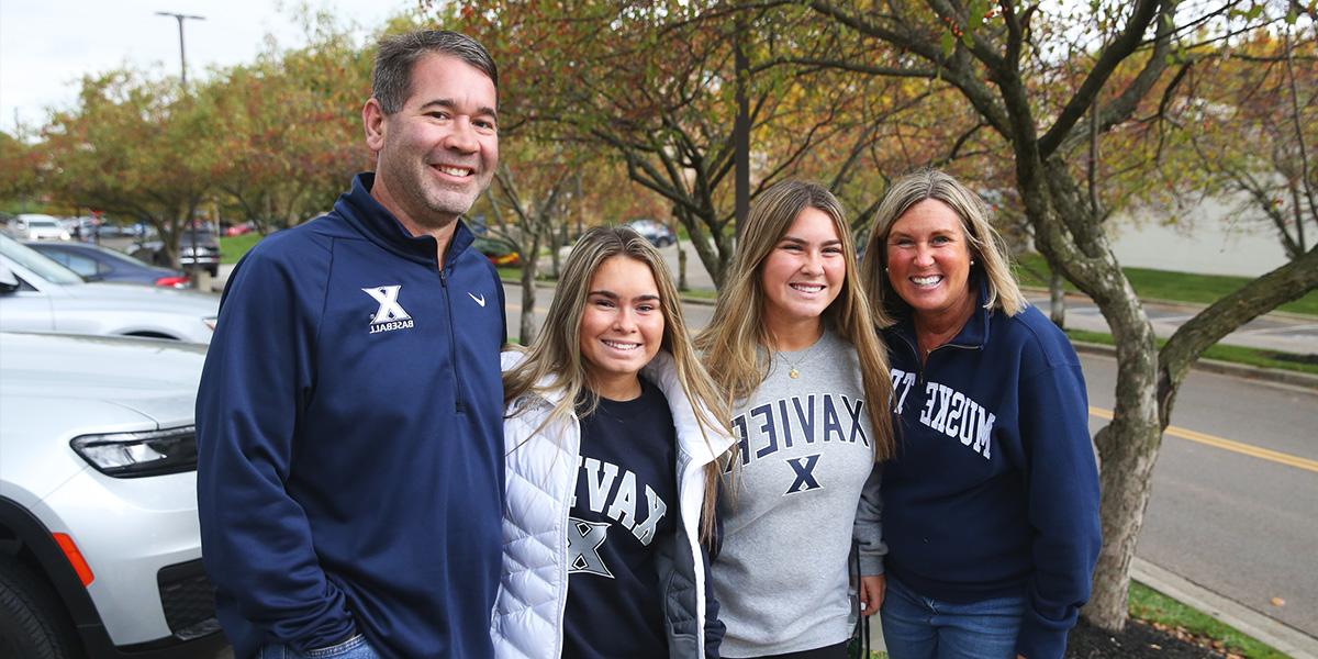 Two Xavier students smiling with their parents.